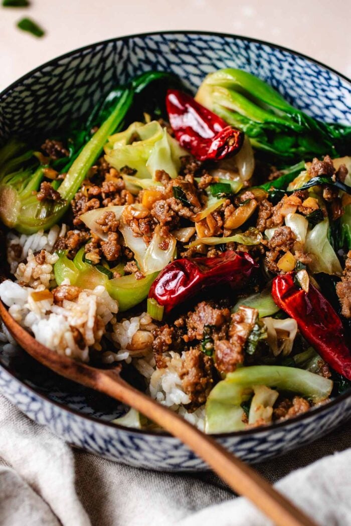 Ground pork stir fried with cabbage and bok choy served with rice in a bowl.