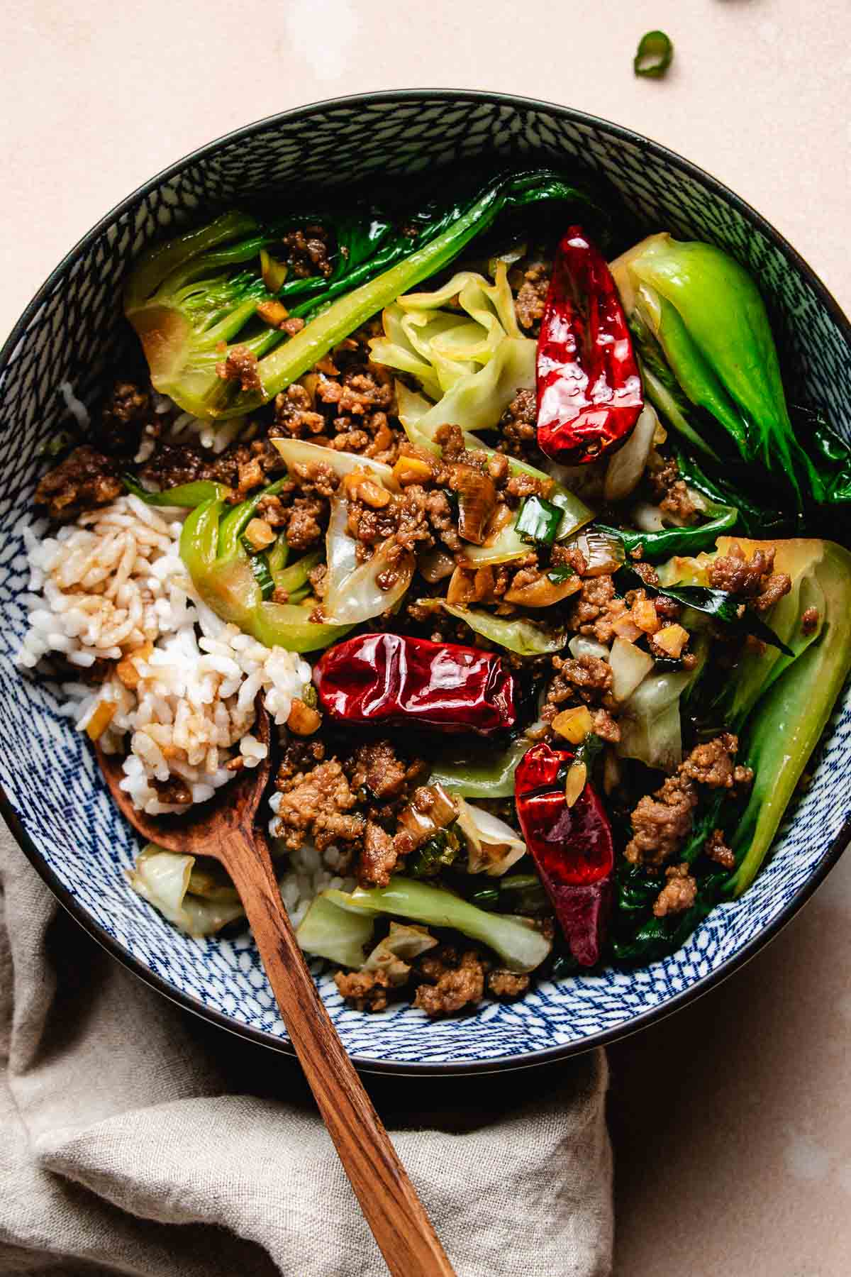 An overhead shot image shows crisp ground pork stir fried with cabbage and bok choy, served with rice to make a pork bowl.