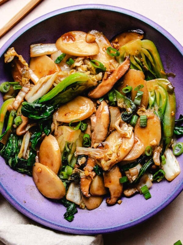 Image shows stir fried Shanghai rice cake with napa cabbage and bok choy in Asian brown sauce on a purple color plate.