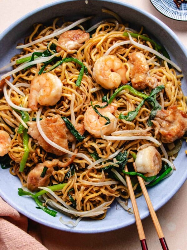 Image shows crispy chow mein noodles house special with chicken and shrimp served in a light blue color plate.