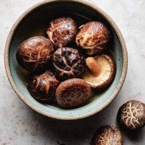 Photo shows a bowl of rehydrated dried shiitake mushrooms soaking in the liquid.