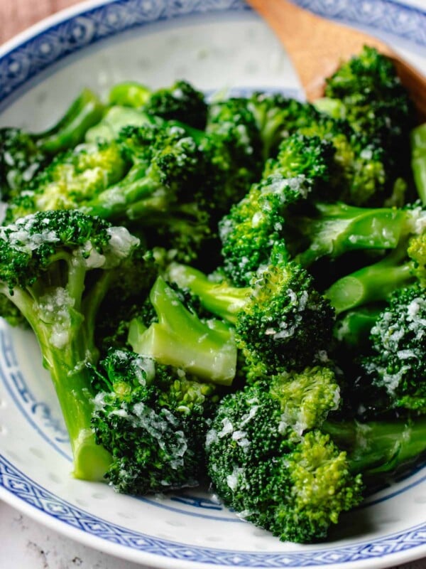 Feature image shows garlic broccoli that is tender and coated with garlic sauce and served in a blue white color plate.