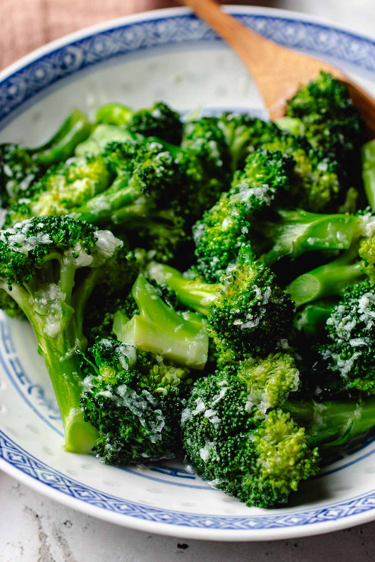 Feature image shows garlic broccoli that is tender and coated with garlic sauce and served in a blue white color plate.