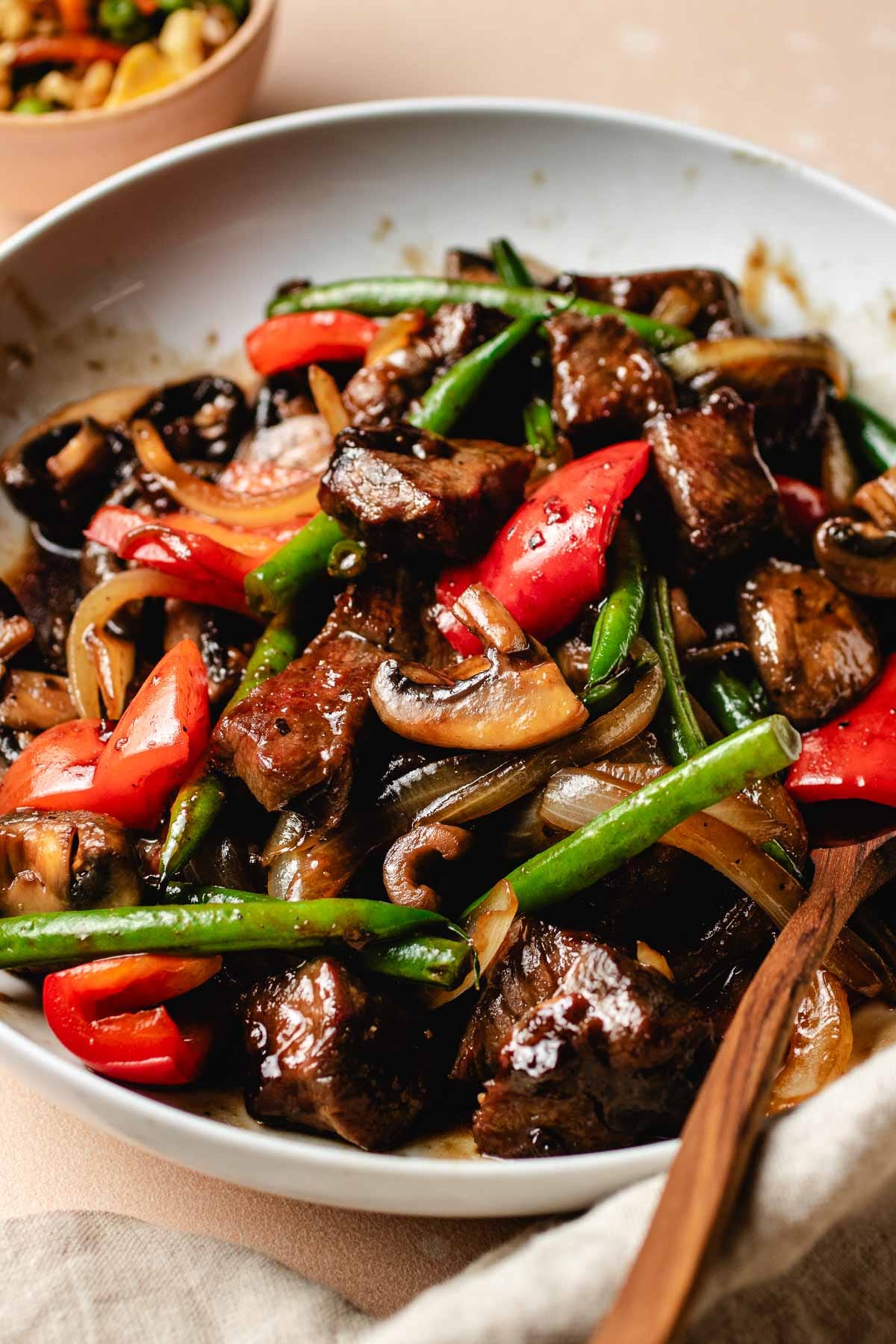 A side shot shows Panda Express black pepper angus steak dish with tender beef cubes and crispy veggies made gluten-free in a white serving plate.