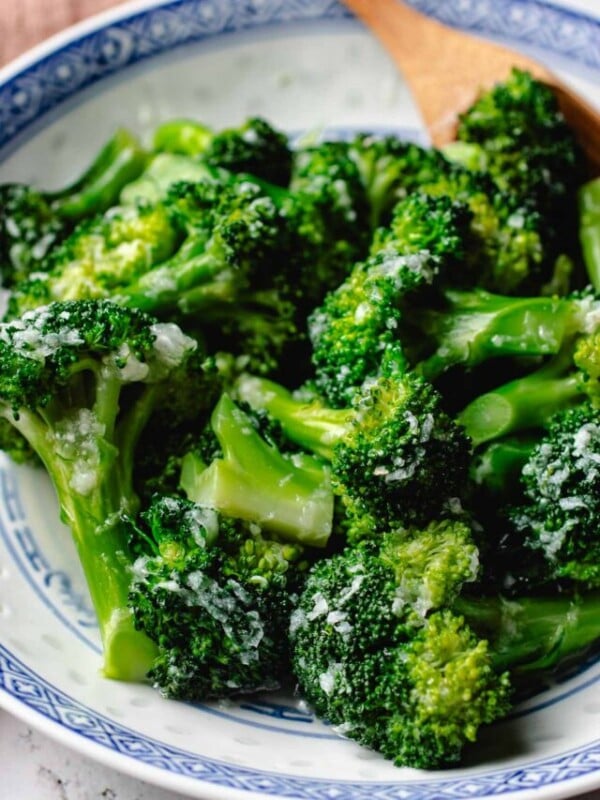 Feature image shows garlic broccoli that is tender and coated with garlic sauce and served in a blue white color plate.