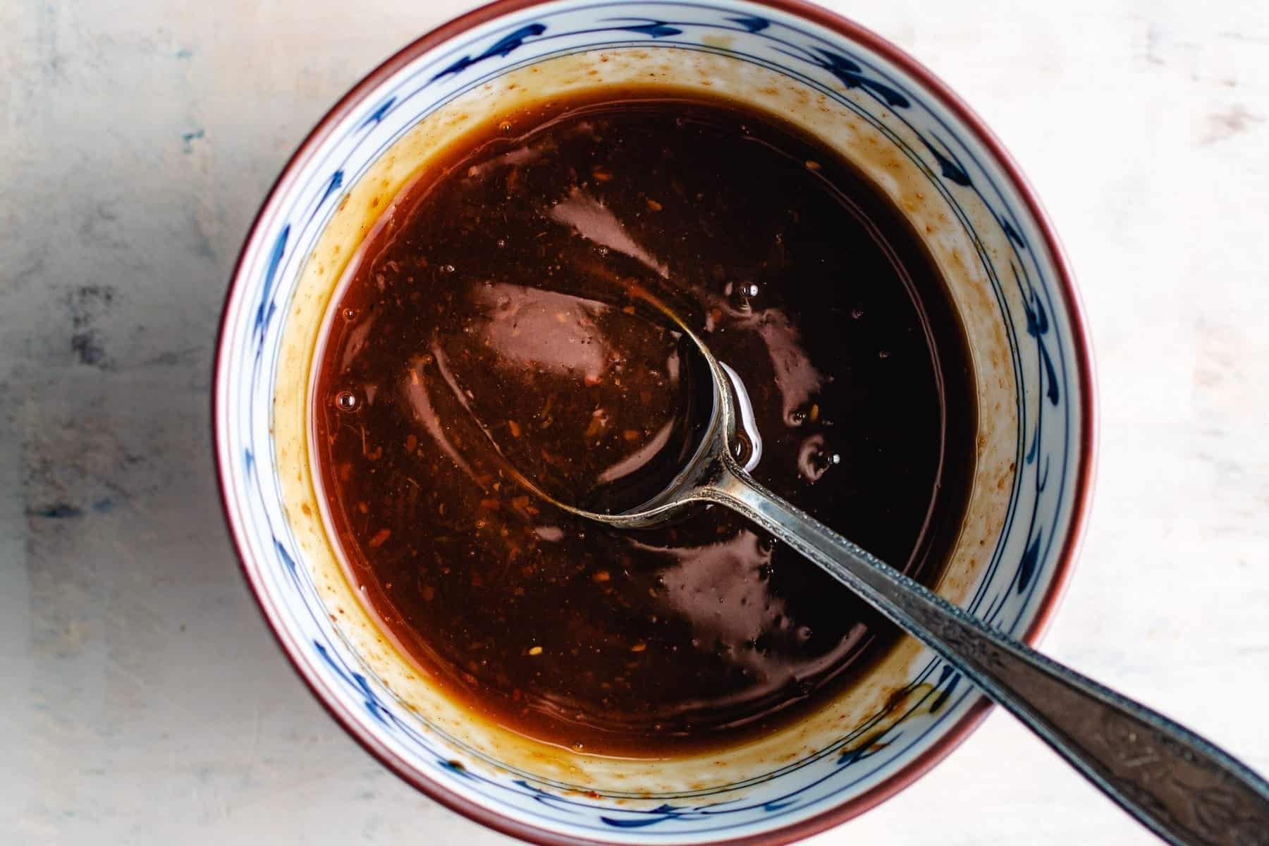 Photo shows honey sriracha sauce made with healthy ingredients and mixed in a small bowl.