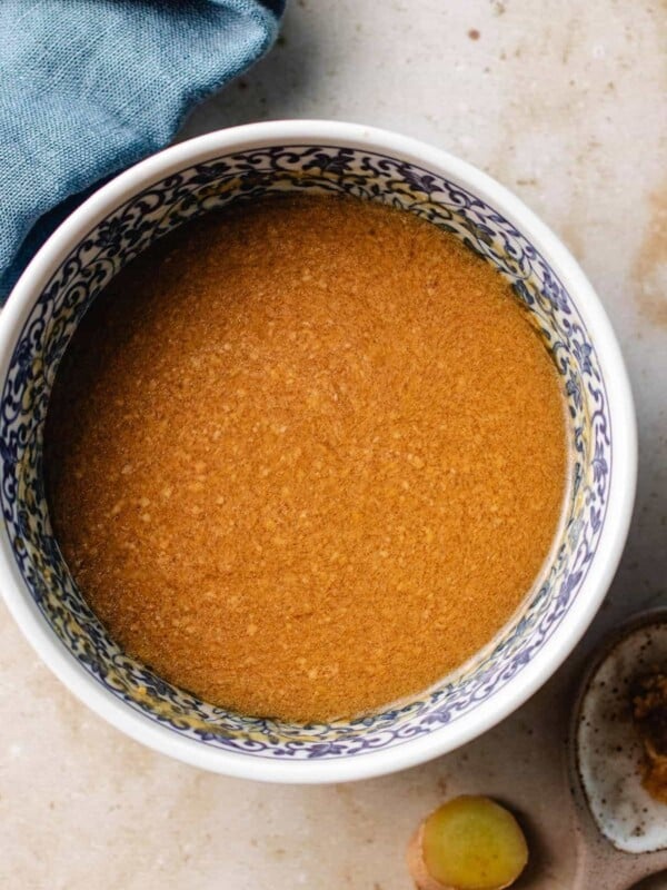 Feature image shows a bowl of creamy miso ginger dressing in a blue white color bowl.