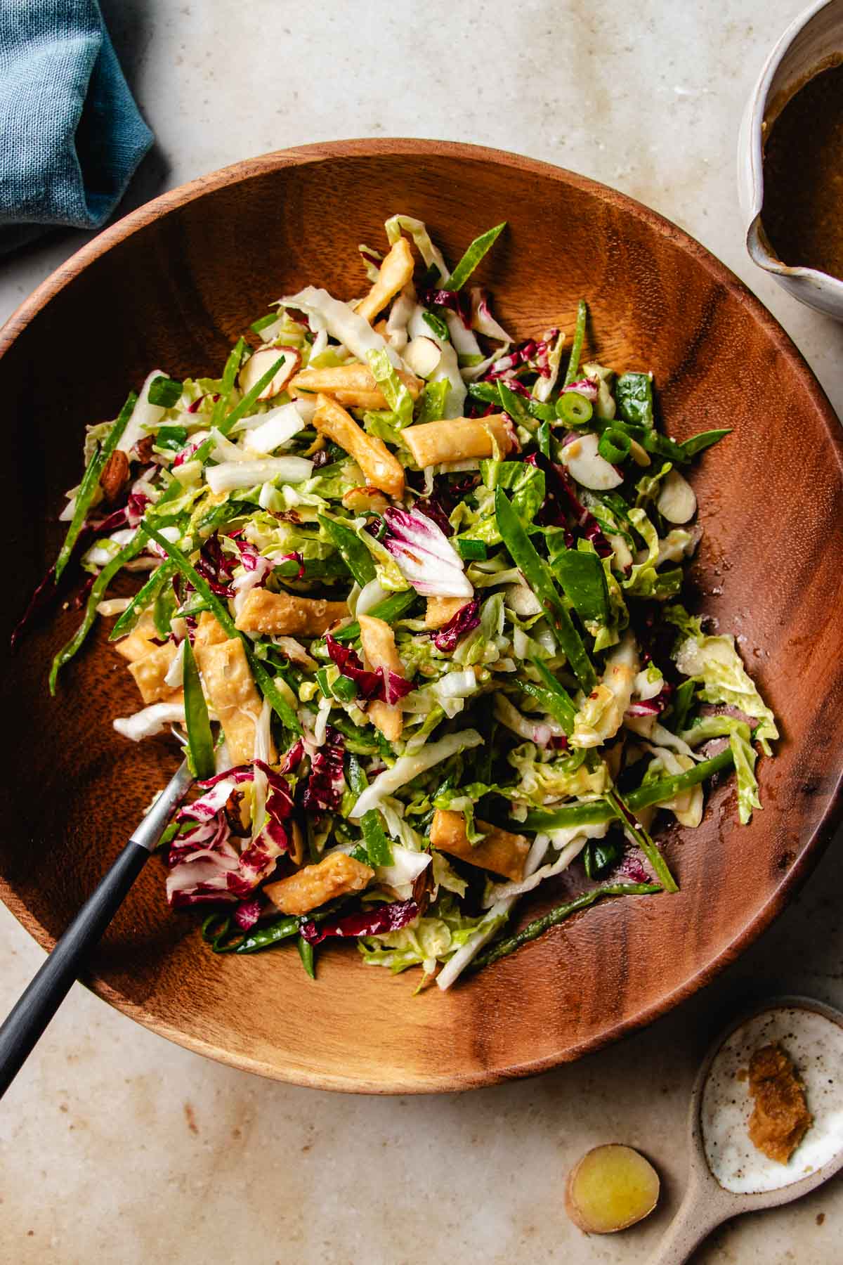 Feature image shows napa cabbage slaw served in a wood plate and tossed with dressing.