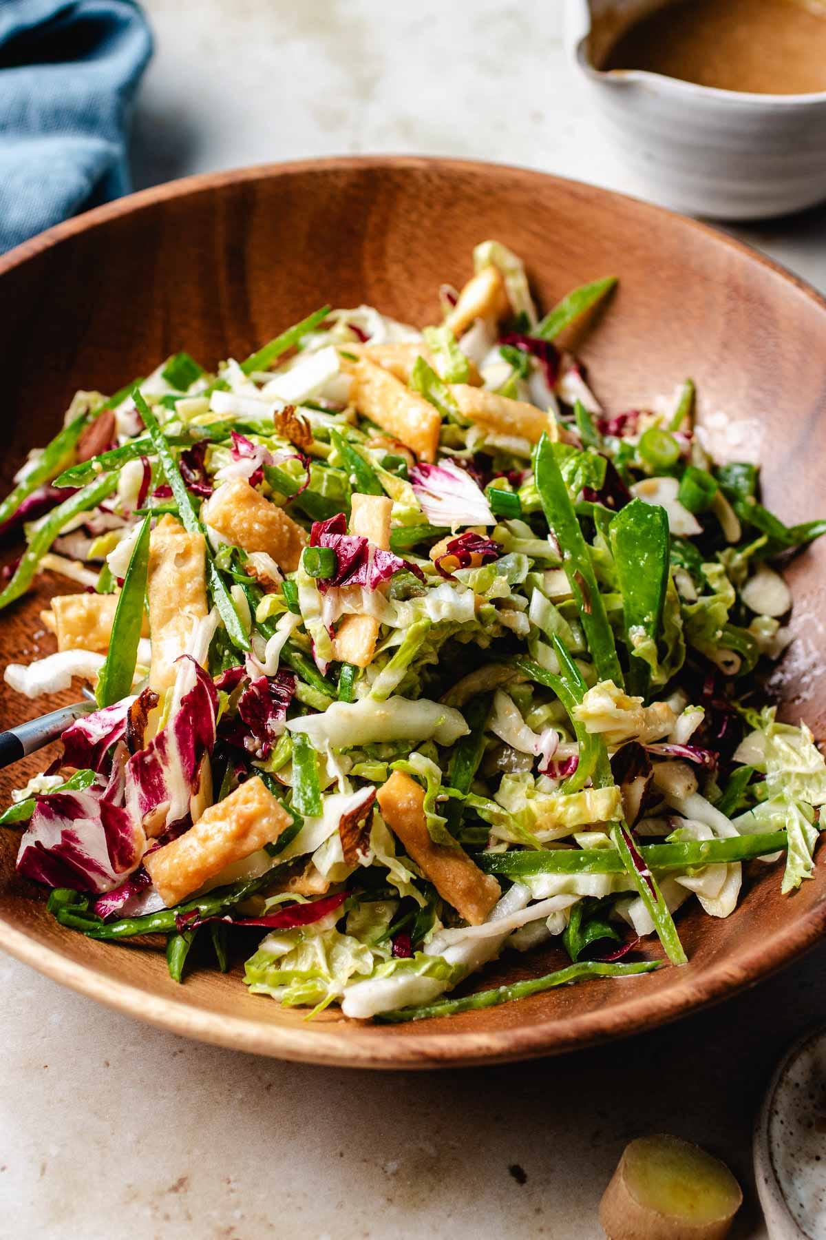 A side shot image shows a bowl of napa cabbage slaw served with miso ginger dressing on the side.