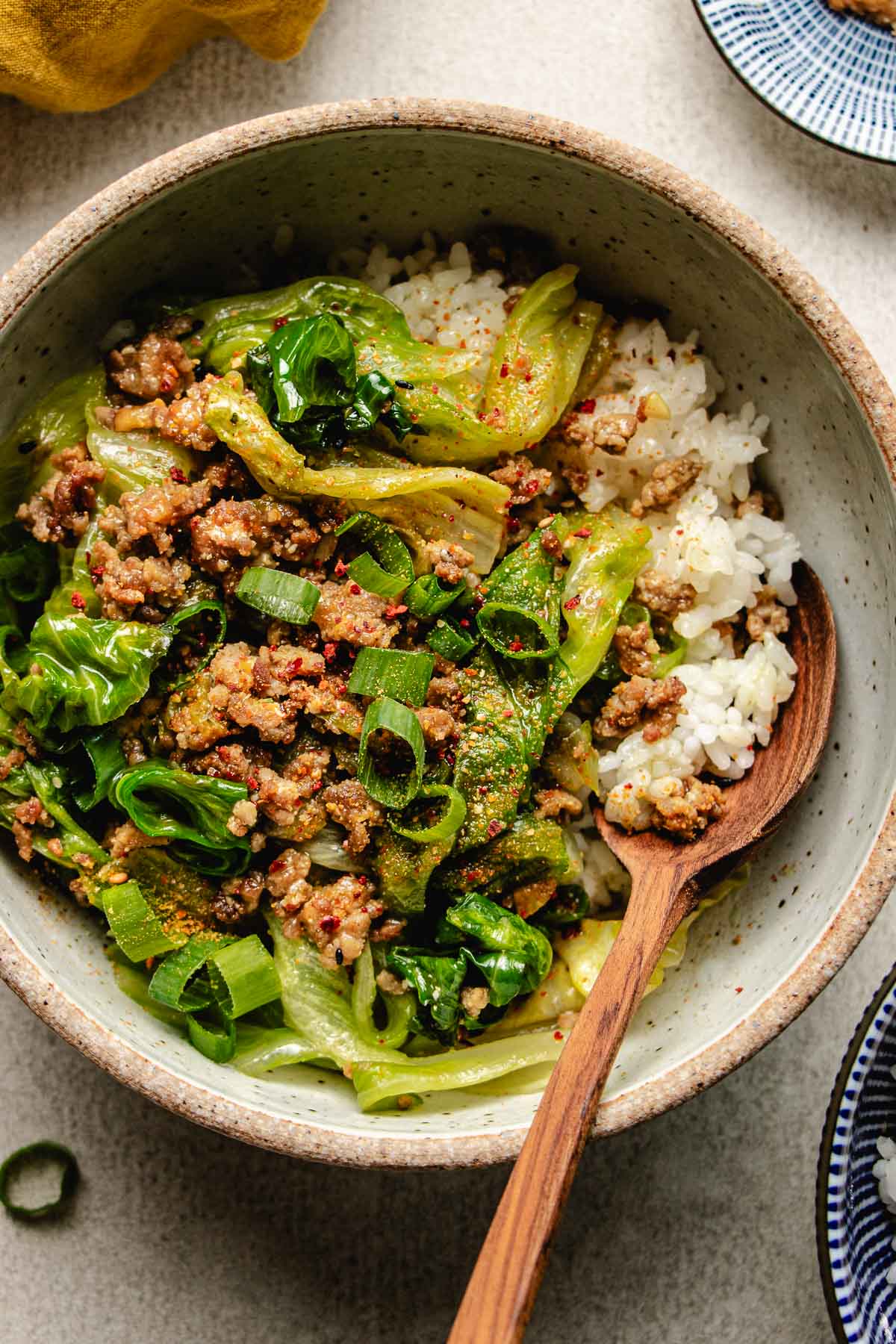 An overhead close shot image shows a bowl of delicious ground pork stir fry with miso sauce and crisp lettuce served over rice.