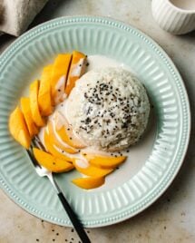 Feature image shows coconut sticky rice with mango served on a light blue color plate with sticky rice sauce.