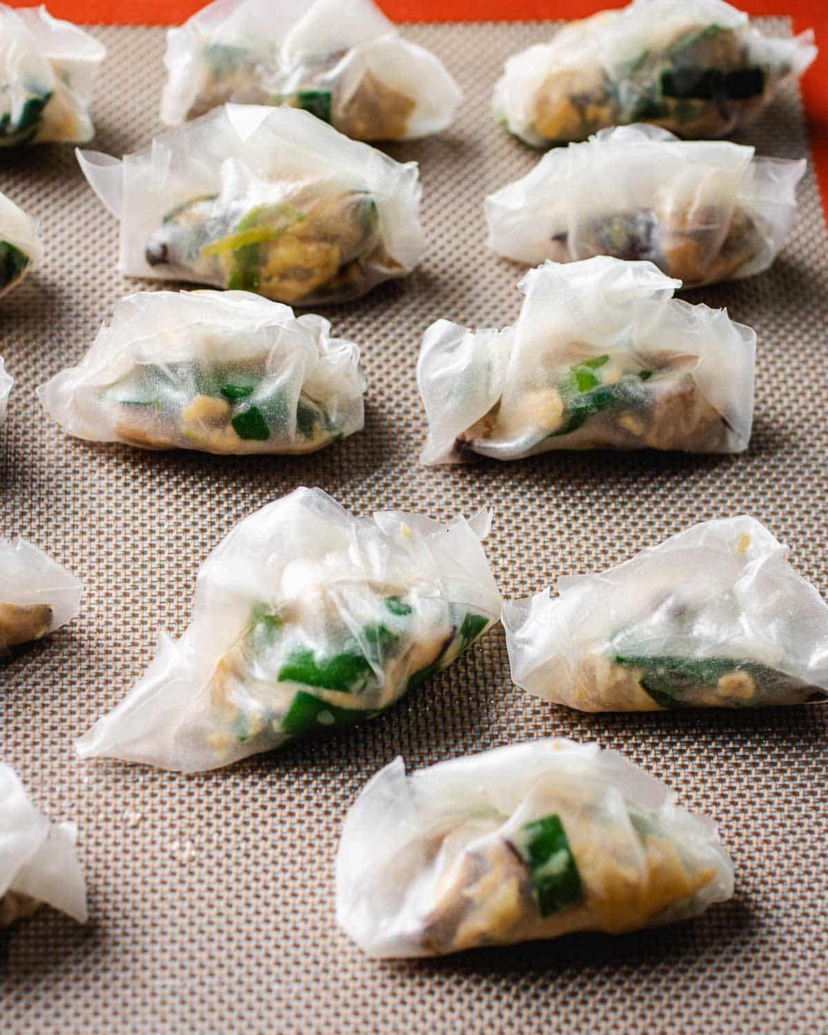 Image shows rice wrapper wrapped chive egg dumplings before frying.