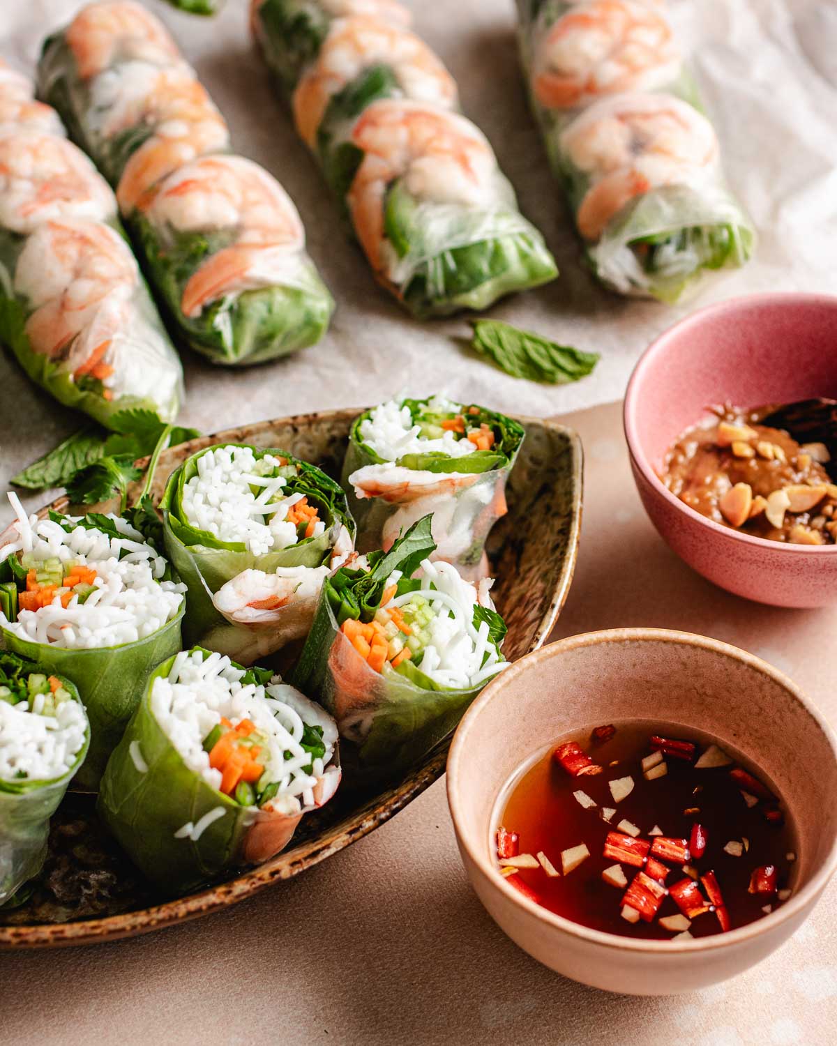 A side shot shows fresh spring rolls with peanut dipping sauce on the side.