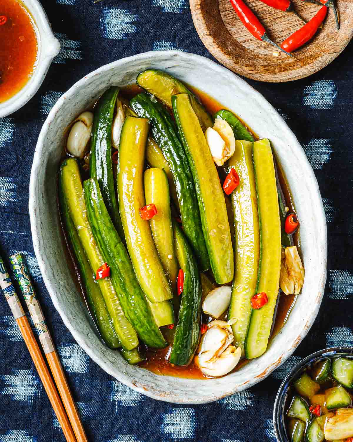 Feature image shows Persian cucumbers sliced to spears and marinated with Asian pickling juice and served in a white oval plate.