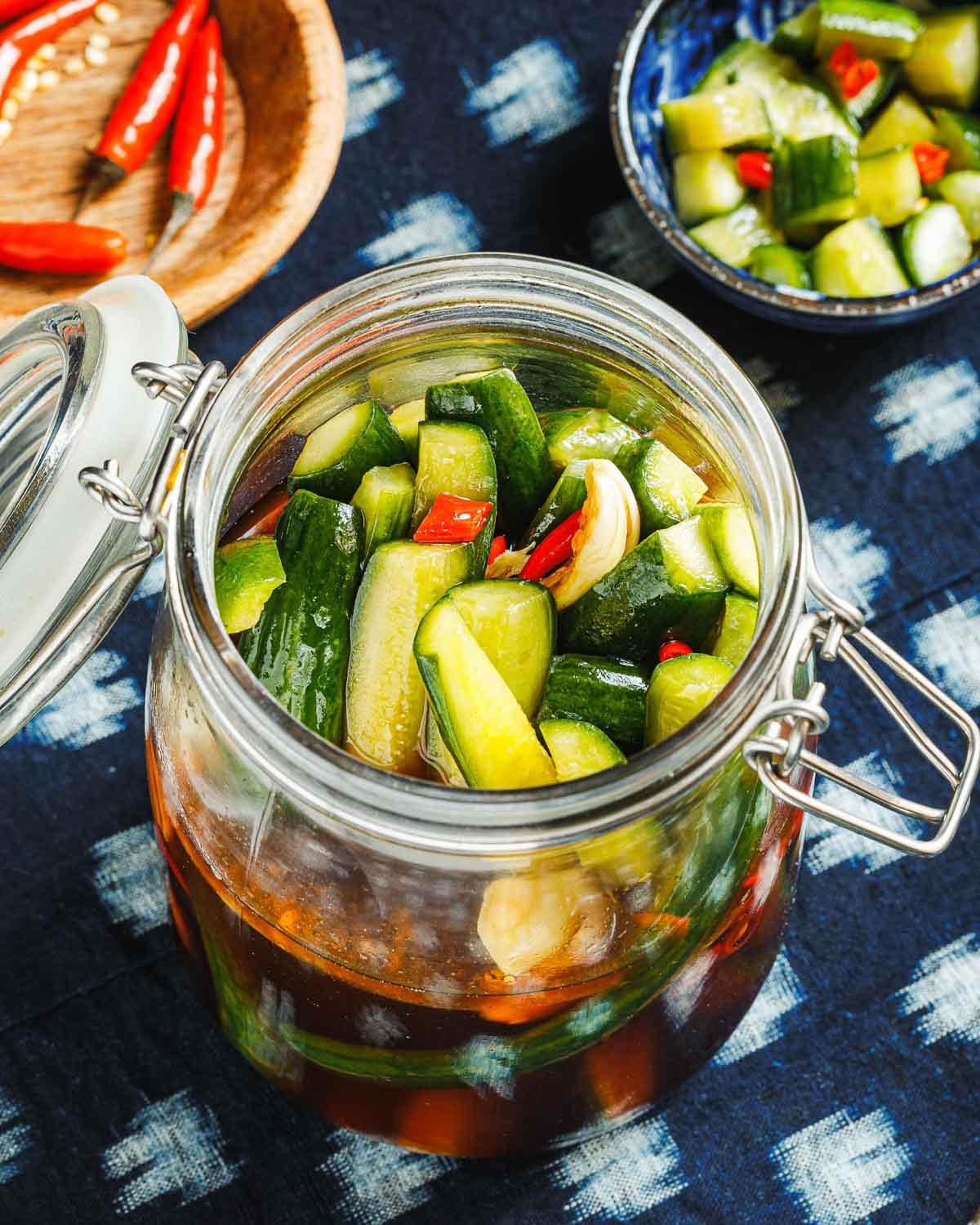 A close shot from the side to show spears of cucumbers packed in an airtight glass jar with pickling juice inside.