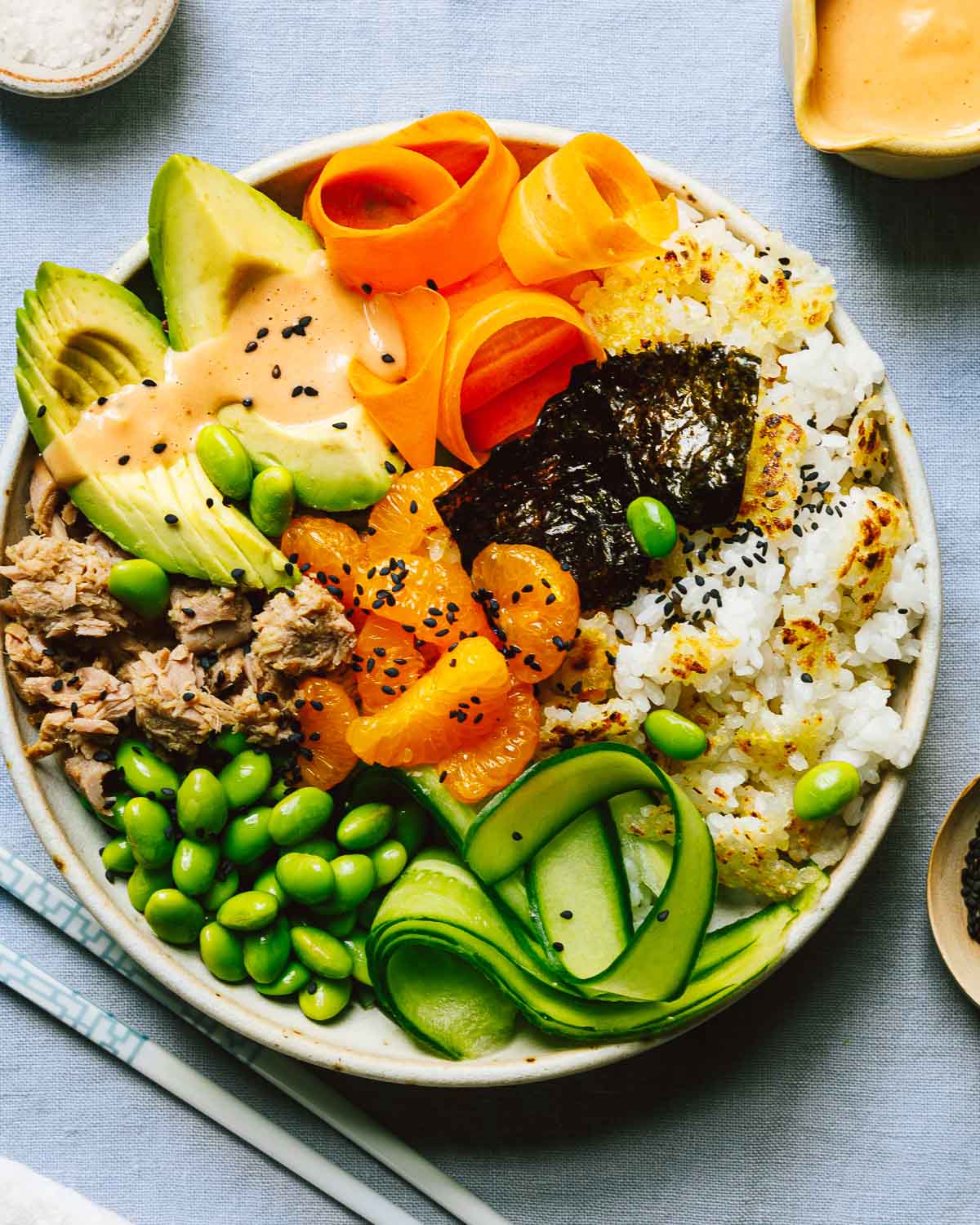 An overhead shot shows spicy tuna bowl with crispy rice and vegetables.