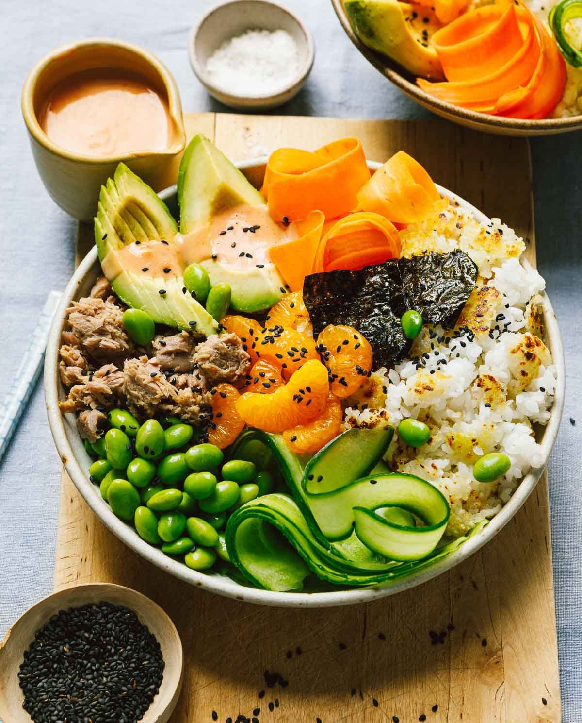 A close shot image shows a bowl of crisp rice with spicy canned tuna and spicy bang bang sauce drizzled over.