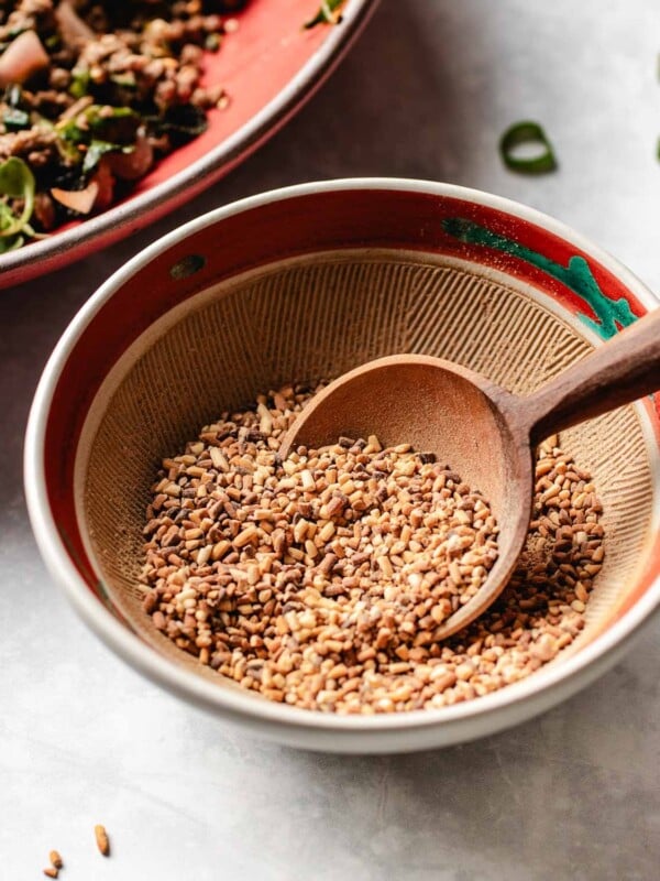 Feature image shows a bowl with toasted rice powder made with glutinous rice as a topping for Thai larb.