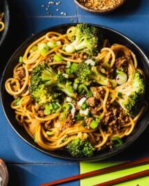 Image shows a plate of ground beef and noodle stir fried with broccoli. Served with chopsticks on the side.