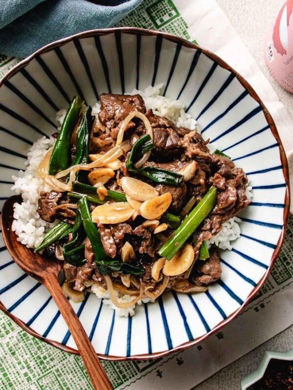 An overhead image shows Chinese beef with garlic sauce with tender beef stir fried in rich garlic sauce, served over a bowl of white rice.