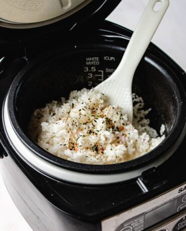 Image shows fluffy white rice made from a rice cooker and fluff with a rice paddle.