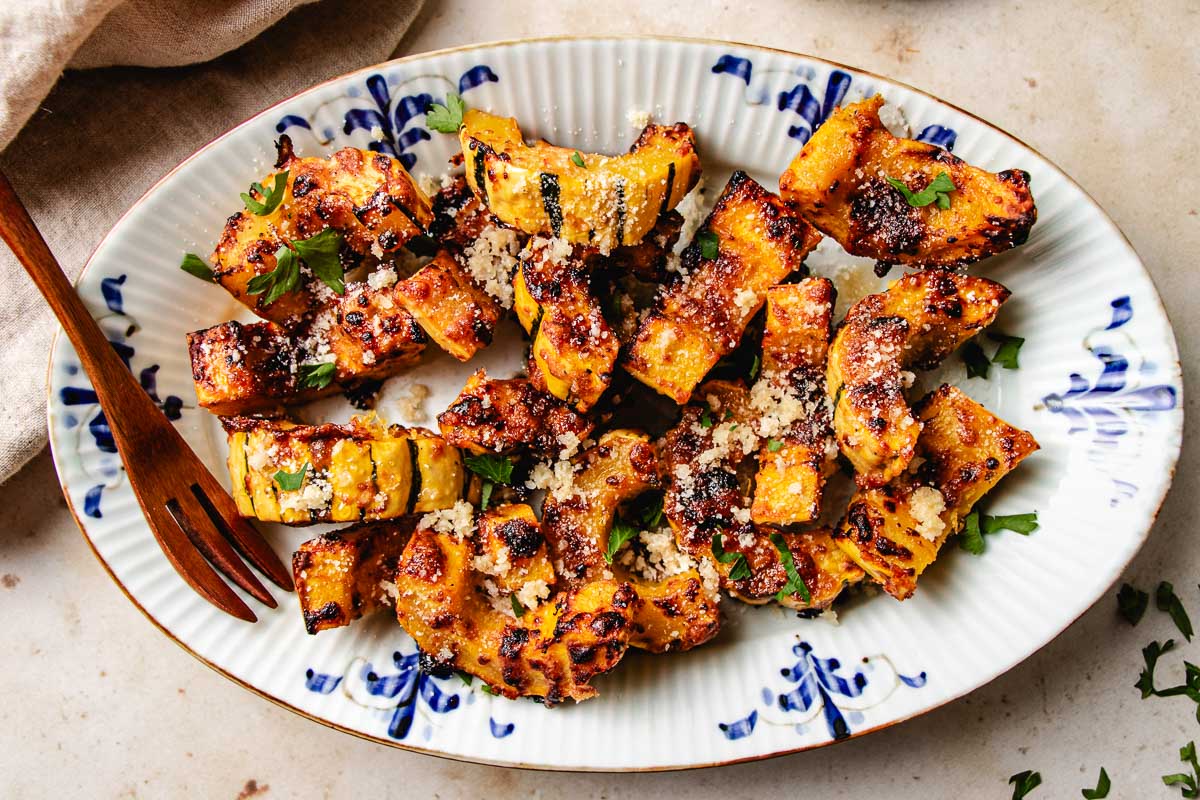 Image shows an oval blue white color plate with golden air fried sweet delicata squash.