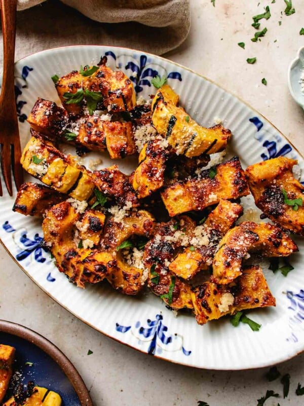 Feature image shows perfectly air fried delicata squash with honey parmesan crust served on a blue white color plate.