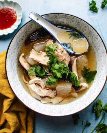 Image shows a bowl of Chinese winter melon soup with chicken and shiitake in a soup bowl.