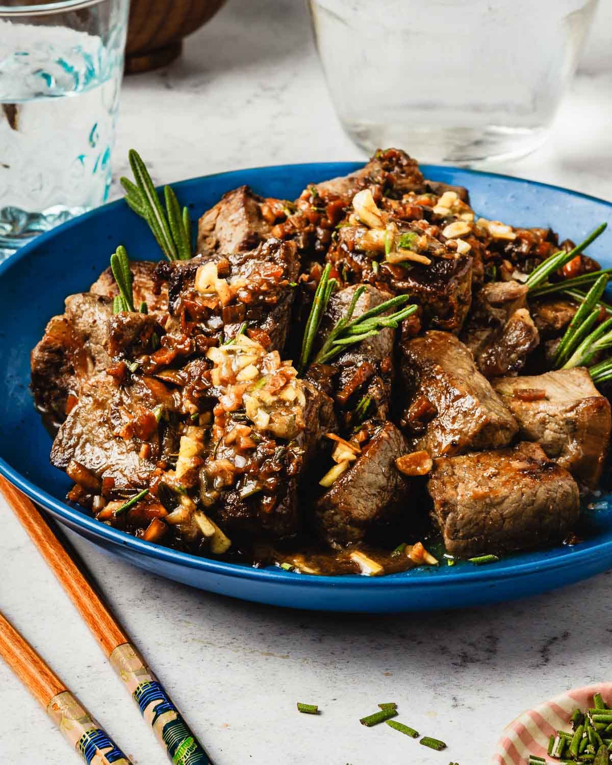 A side close shot shows perfectly seared steak bites covered with garlic butter sauce.