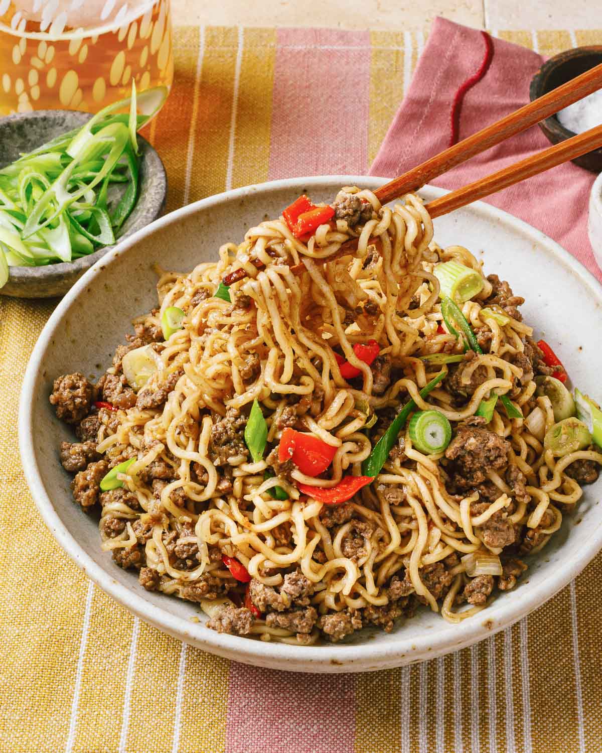 A side close shot shows pulling noodles up from the dish to eat.