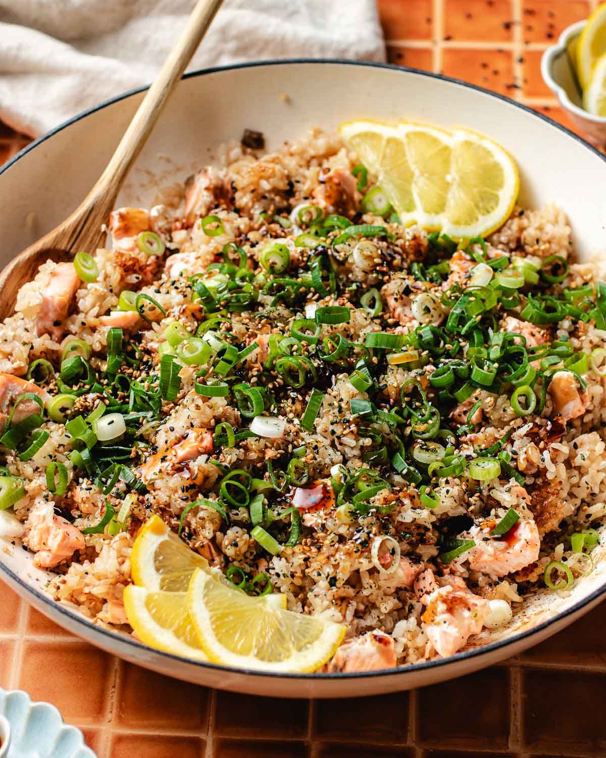 A side close shot shows the perfectly cooked crispy rice with tender salmon, served in a big pan.