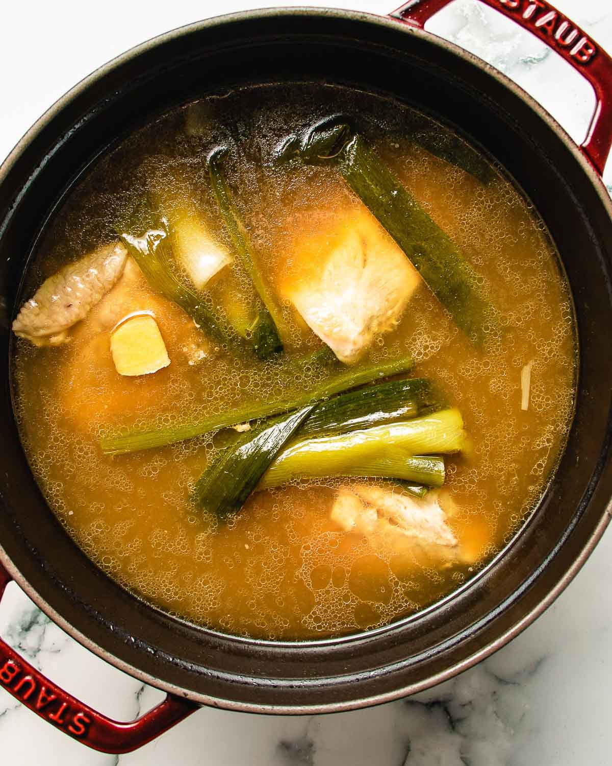 An overhead image shows simple chicken hot pot broth.