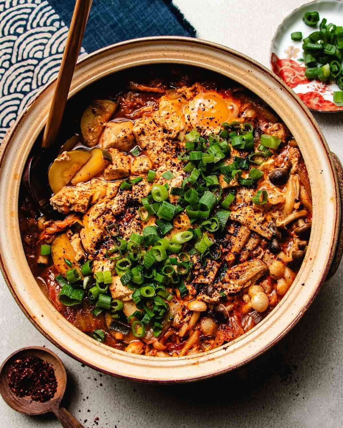 Image shows a pot of spicy kimchi broth for hot pot in a round shape clay pot.