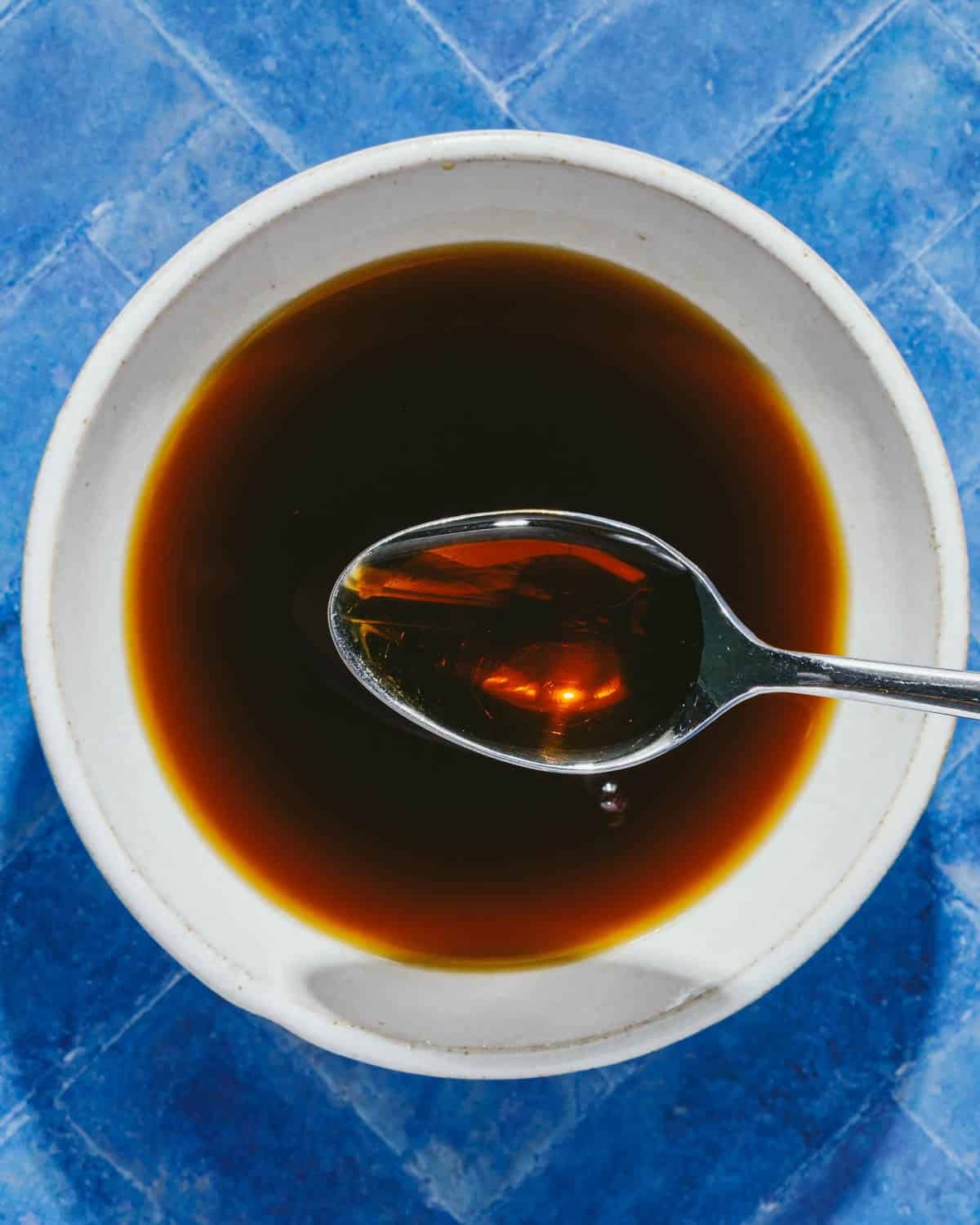 Feature overhead image shows a white sauce bowl with gluten free teriyaki sauce inside with a spoon.