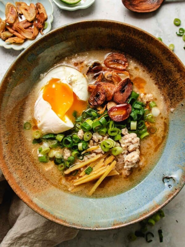 An overhead feature image shows a bowl of delicious Creamy chicken and rice soup Taiwanese style with garlic chips, ginger, green onions, and a poached egg served in one bowl.