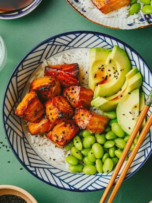 Feature overhead image shows a bowl of teriyaki salmon bites with teriyaki sauce served in a rice bowl.