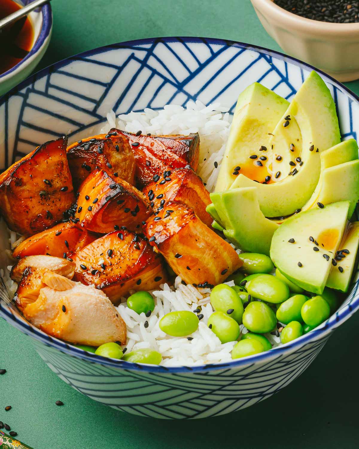 A side shot shows juicy salmon bites drizzled with teriyaki sauce served in a rice bowl.