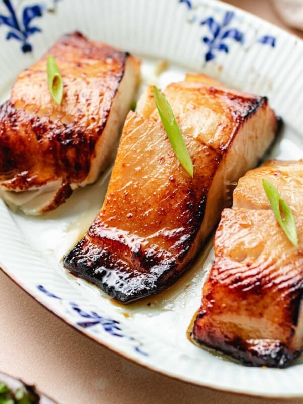 Feature image shows caramelized black cod fillets marinated with miso glaze and served on a blue white color plate.