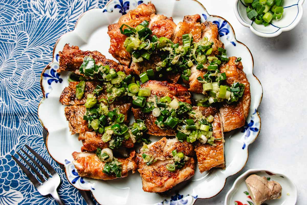 A horizontal image shows crispy scallion chicken served over a blue white color plate.