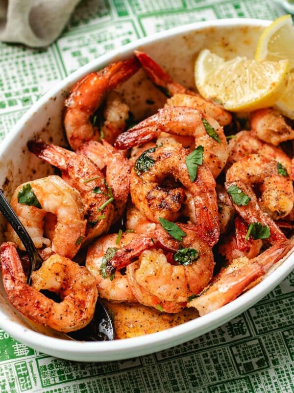 Feature image shows air fryer frozen shrimp cooked to perfection in a baking dish with garlic, butter, paprika, and lemon drizzle on top.