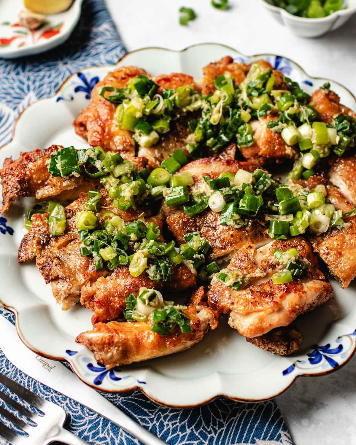 A side close shot shows scallion chicken with crispy skin and topped with ginger scallion sauce.