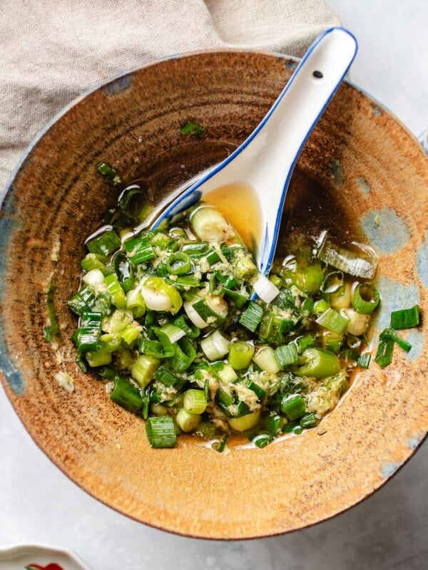 Feature image shows a ceramic bowl filled with ginger scallion sauce and serve with a spoon.