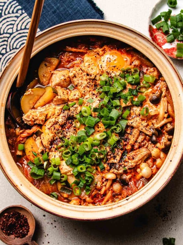 Feature overhead image shows silken tofu stewed with kimchi and vegetables in a big donabe soup pot.