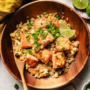 Recipe image for Thai salmon fried rice garnished with lime and sauce on the side.