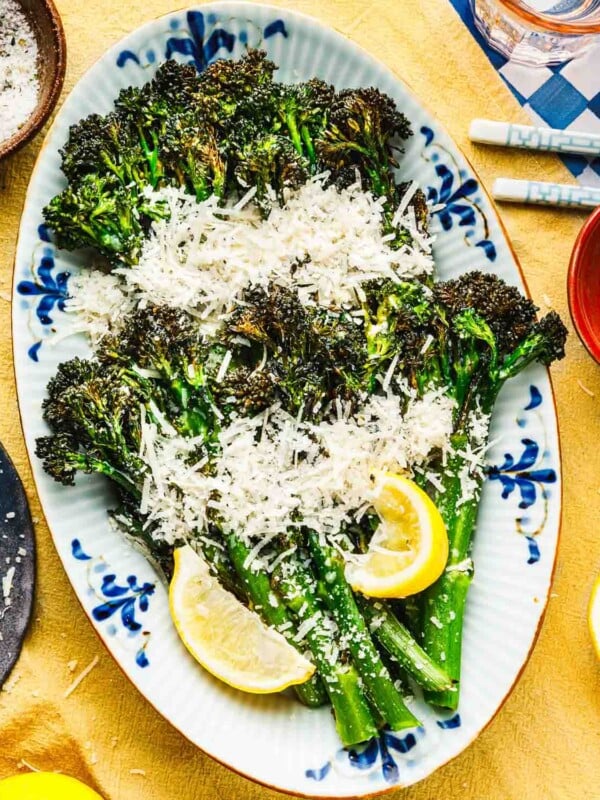 Feature overhead image shows a plate of air fried broccolini to tender and crisp, garnished with lemon, grated garlic parmesan.