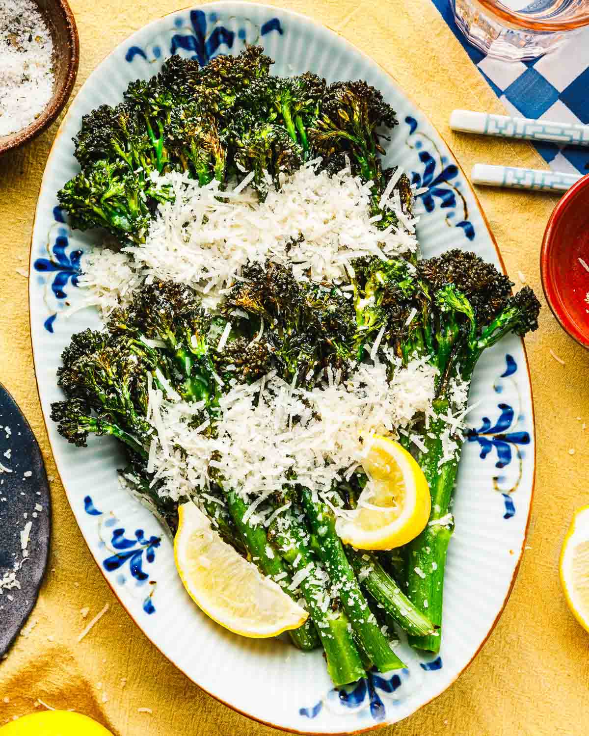 Feature overhead image shows a plate of air fried broccolini to tender and crisp, garnished with lemon, grated garlic parmesan.