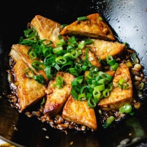 Recipe image with braised tofu (hong shao tofu) and sweet soy brown sauce in a hot wok.