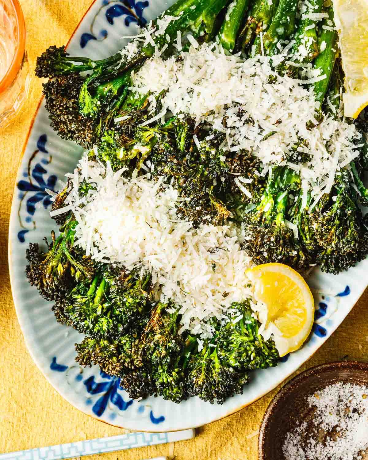 A close overhead shot shows perfectly air fried broccolini served with grated parmesan and lemon.