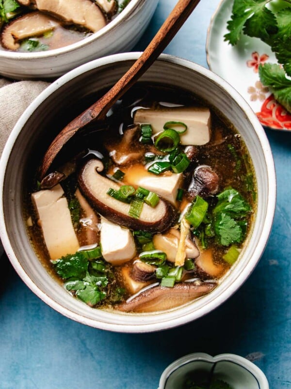 Feature image shows a bowl of shiitake mushroom soup served in a white color bowl with silken tofu.