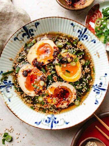 Feature image shows a bowl of soy egg sauce with eggs marinated inside with soft egg yolk center.